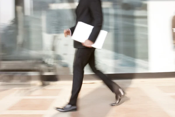Affärsman med en laptop promenader — Stockfoto