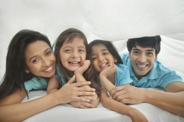Family smiling under blanket — Stock Photo, Image