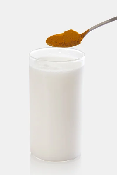 Mléko s lžičku kurkumy prášku — Stock fotografie