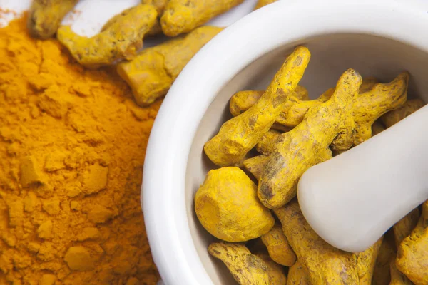 Turmeric roots in a mortar with turmeric powder — Stock Photo, Image