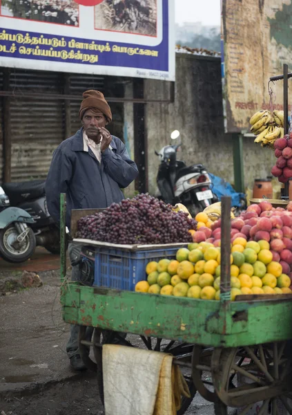 Ooty, Tamilnadu 25 Eylül: yağmurlu gün üzerinde Ooty, Tamilnadu, Hindistan Tarih Eyl 25, 2014 yol kenarına yerleştirilen araç eşya üzerinde meyve satan meyve satıcı