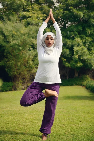 Arap kadın havuz tarafından yoga yaparken