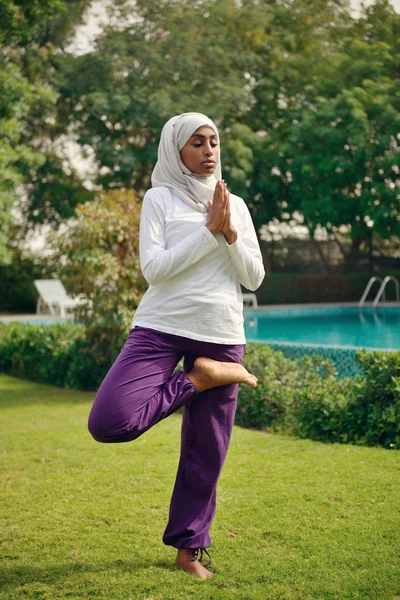 Mujer árabe haciendo yoga junto a la piscina Imagen de archivo