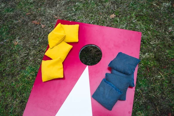 Oyun tahtası üzerinde yığılmış Cornhole fasulye torbaları — Stok fotoğraf