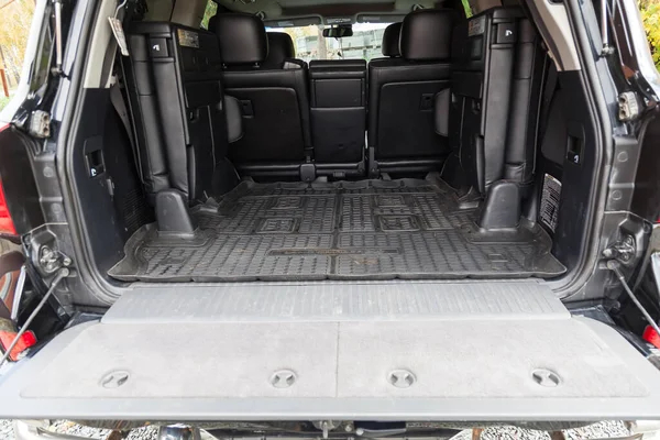Luggage space in the body of the SUV car trunk with rubber mat and open rear door and leather interior after washing and dry cleaning with three rows of seats. Auto service industry. Travel concept.