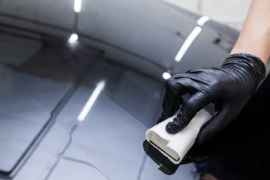 Arabanın kaputuna nano seramik tabaka sürme işlemi. Sünger ve özel kimyasal bileşimi olan bir erkek işçi tarafından. Vücudundaki boyayı çiziklerden, cipslerden ve hasardan korumak için..