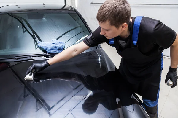 The process of applying a nano-ceramic coating on the car\'s hood by a male worker with a sponge and special chemical composition to protect the paint on the body from scratches, chips and damage.