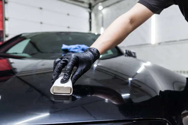 The process of applying a nano-ceramic coating on the car\'s hood by a male worker with a sponge and special chemical composition to protect the paint on the body from scratches, chips and damage.