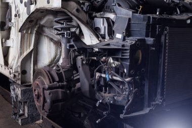 Arabanın ön kısmı, araba tamir servisindeki kazadan sonra parçalanmış kaputu, metal ızgarası ve garaj kutusunun çeşitli parçaları ile birlikte..