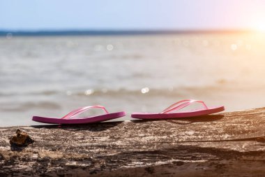 Güneşli bir plajda kırmızı tabanlı bir çift sandalet ve bir yaz günü sahile yakın kumlar. Dinlen ve sıcak ülkelere git. Tatil.