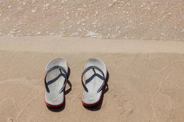 夏の日に海岸近くの砂と日当たりの良いビーチで赤い底のサンダルのペア 休息と暑い国への旅行 — ストック写真