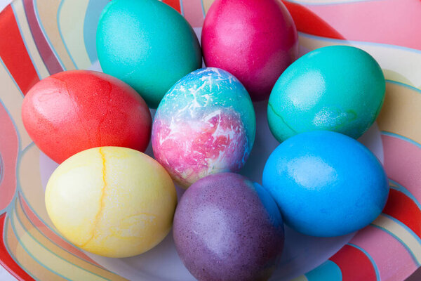 Пасхальный праздник с красочными яйцами на тарелке во время приготовления пищи. Домашняя выпечка.