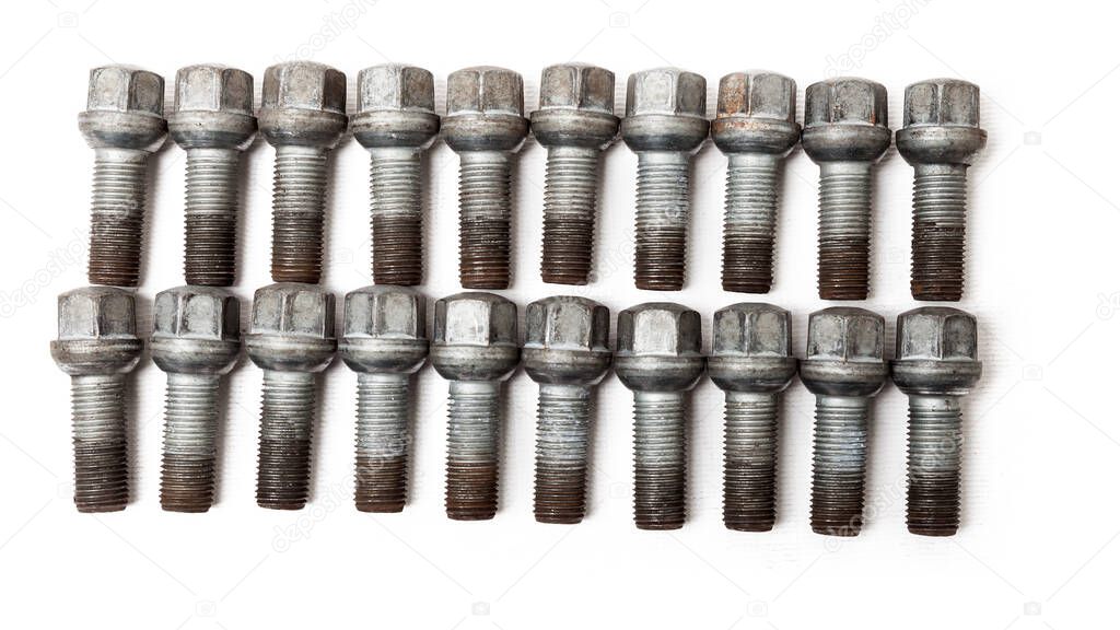 A two rows of metal bolts to fix the wheels and prevent theft of the car on a white background in a photo studio. Spare consumables for replacement during repair or for sale.