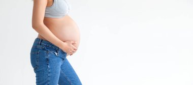 Beyaz bir arka planda, hamile bir kadının karnına pankart şeklinde yakın plan. Hamile kadın ve bebek hastalıklarının tedavisi ve önlenmesi.