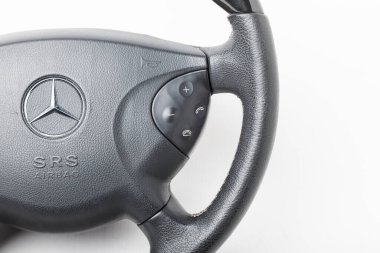 Novosibirsk, Rusya - 10.30.2020: Beyaz izole arka planda siyah ahşap elemente sahip bir Mercedes-Benz direksiyonundan yedek parça ve iç öğe. Otomobil hizmet endüstrisi.