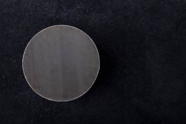 Macro shot of a metal strip catalyst made of heat-resistant chrome-nickel steel. Molten automotive catalytic converter lies on the table, cut into two parts. Pices of broken catalytic converter