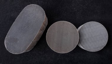 Three round and oval ceramic catalysts containing platinum, palladium and rhodium on a black background. Processing and acceptance of non-ferrous metals. clipart