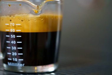 Kapatın ve makro crema robusta kahve İtalyan rostosu kahve bardağına kahve fincanı dolduran kahve makinası tek bardakta ve kahveci kafede barista tarafından duble shot.