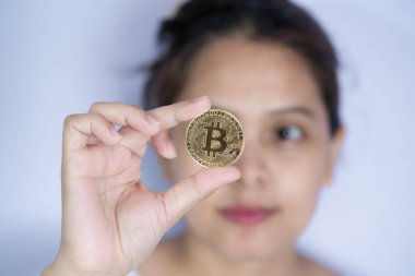 Ellerinde kripto para olan altın bitcoin ile çalışan kadınlar Asyalı kadınların gözünün önünde ve yüzünde bitcoin tutuyorlardı. Engelleme teknolojisi gelecek para Yakın çekim ve Makro fotoğrafçılık konsepti.