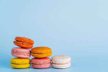 Makaron ya da badem kurabiyesi tatlıları ve renkli Fransız tatlıları mavi arkaplanda izole edilmiş klasik renk ya da pastel renktir. Kapat ve Makro fotoğrafçılık.