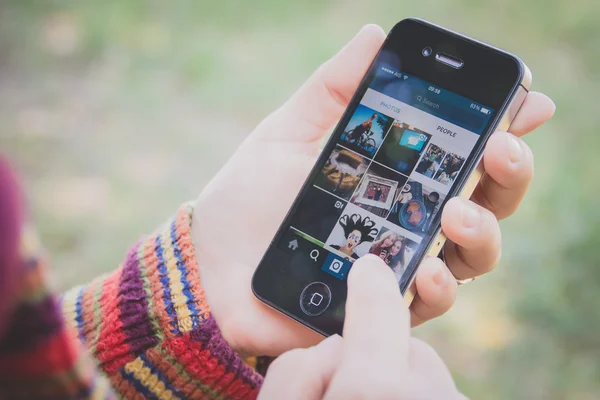 Tangan memegang Iphone dan menggunakan aplikasi Instagram — Stok Foto