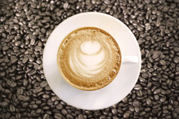 Cappuccino quente com xícara branca em grãos de café — Fotografia de Stock