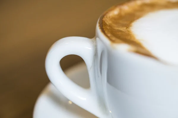 Cappuccino quente com copo branco na casa de café de mesa de madeira — Fotografia de Stock
