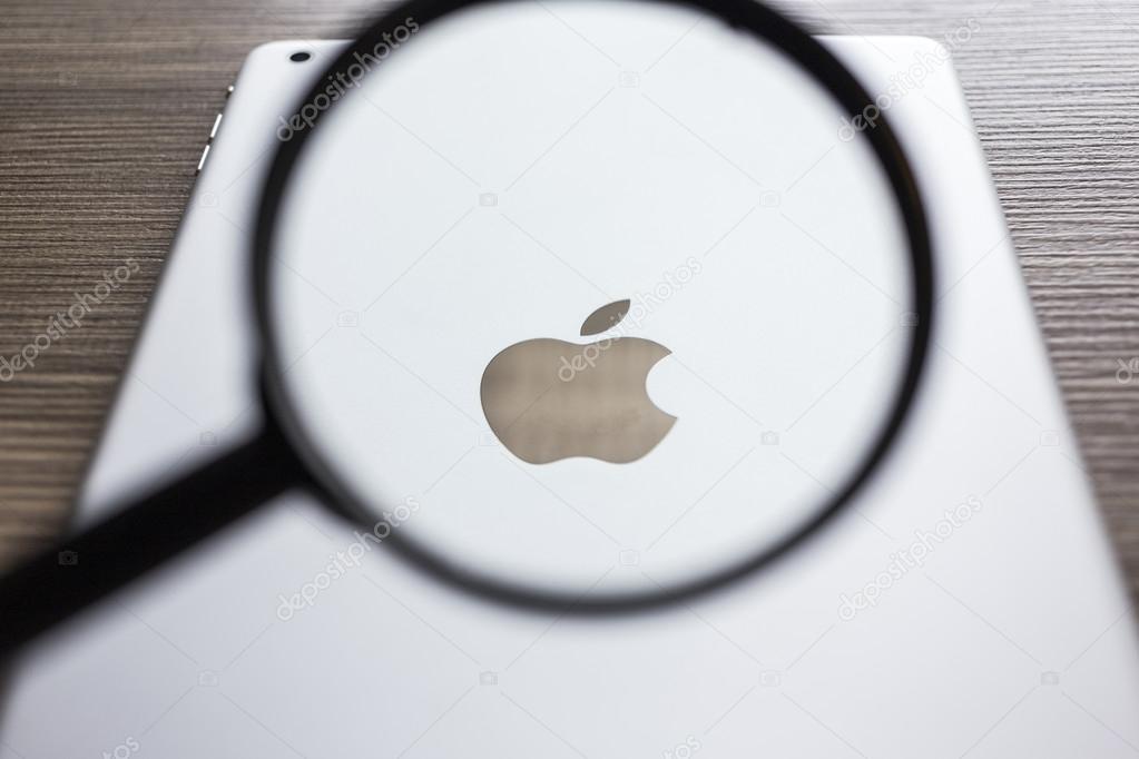 CHIANG MAI, THAILAND - OCTOBER 21, 2014: Magnification glass focus on Logo of Apple in back Apple iPad air on wood desk.