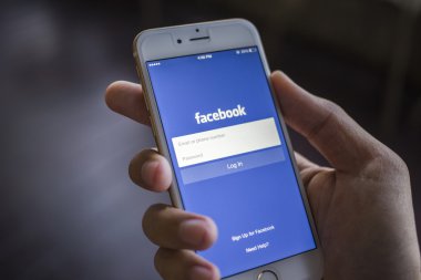 CHIANG MAI, THAILAND - JANUARY 02, 2015: A man trying to log in Facebook application using Apple iPhone 6. Facebook is largest and most popular social networking site in the world.
