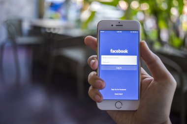 CHIANG MAI, THAILAND - JANUARY 02, 2015: A man trying to log in Facebook application using Apple iPhone 6. Facebook is largest and most popular social networking site in the world.