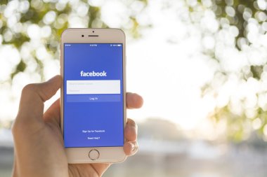 CHIANG MAI, THAILAND - JANUARY 04, 2015: A man trying to log in Facebook application using Apple iPhone 6. Facebook is largest and most popular social networking site in the world.