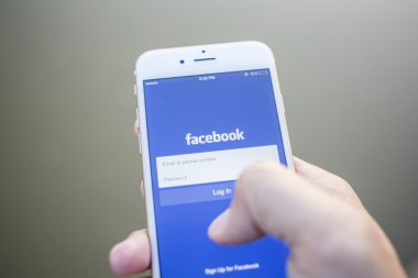 CHIANG MAI, THAILAND - JANUARY 02, 2015: A man trying to log in Facebook application using Apple iPhone 6. Facebook is largest and most popular social networking site in the world.
