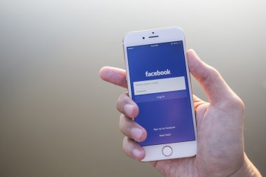 CHIANG MAI, THAILAND - JANUARY 02, 2015: A man trying to log in Facebook application using Apple iPhone 6. Facebook is largest and most popular social networking site in the world.