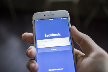 CHIANG MAI, THAILAND - JANUARY 02, 2015: A man trying to log in Facebook application using Apple iPhone 6. Facebook is largest and most popular social networking site in the world.