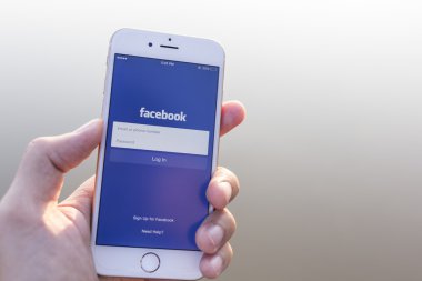 CHIANG MAI, THAILAND - JANUARY 02, 2015: A man trying to log in Facebook application using Apple iPhone 6. Facebook is largest and most popular social networking site in the world.