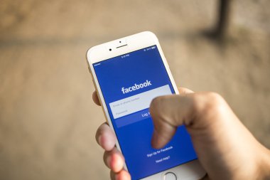CHIANG MAI, THAILAND - JANUARY 04, 2015: A man trying to log in Facebook application using Apple iPhone 6. Facebook is largest and most popular social networking site in the world.