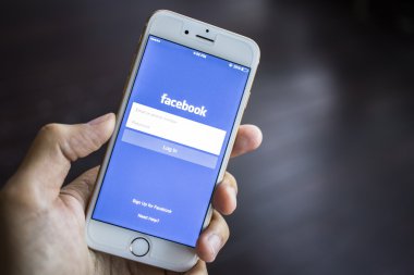 CHIANG MAI, THAILAND - JANUARY 02, 2015: A man trying to log in Facebook application using Apple iPhone 6. Facebook is largest and most popular social networking site in the world.