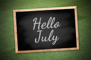 Hello July concept on chalk board and green field background and texture