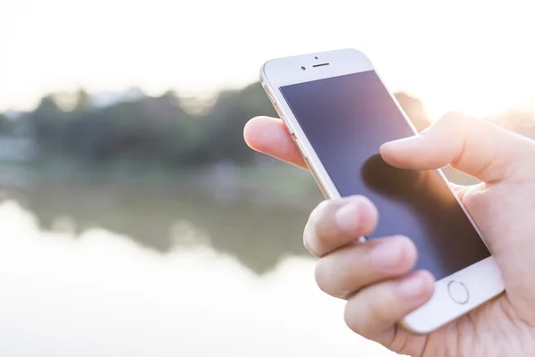 Man hand met smartphone tegen op gladde achtergrond. — Stockfoto