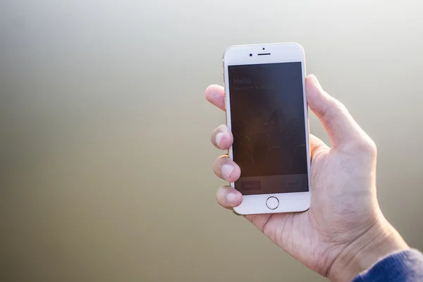 Man hand met smartphone tegen op gladde achtergrond. — Stockfoto