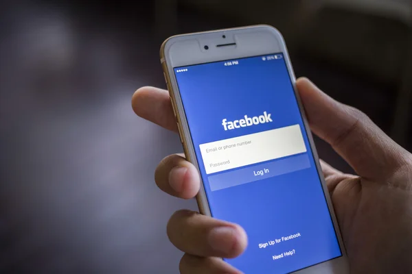 CHIANG MAI, THAILAND - JANUARY 02, 2015: A man trying to log in Facebook application using Apple iPhone 6. Facebook is largest and most popular social networking site in the world. — Stock Photo, Image