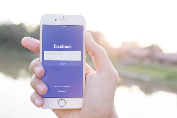 CHIANG MAI, TAILANDIA - 02 DE ENERO DE 2015: Un hombre que intenta iniciar sesión en la aplicación de Facebook usando Apple iPhone 6. Facebook es el sitio de redes sociales más grande y popular del mundo . — Foto de Stock