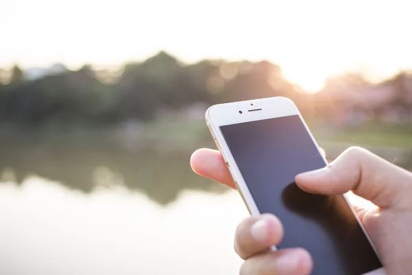 Mann hält Smartphone vor glatten Hintergrund. — Stockfoto