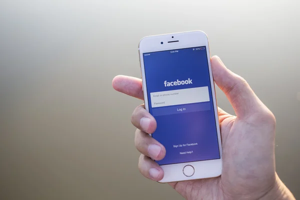 CHIANG MAI, THAILAND - JANUARY 02, 2015: A man trying to log in Facebook application using Apple iPhone 6. Facebook is largest and most popular social networking site in the world. — Stockfoto