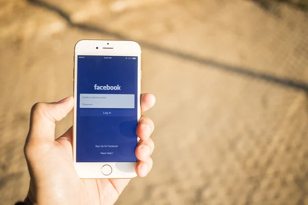 CHIANG MAI, THAILAND - JANUARY 04, 2015: A man trying to log in Facebook application using Apple iPhone 6. Facebook is largest and most popular social networking site in the world. — Stock Photo, Image