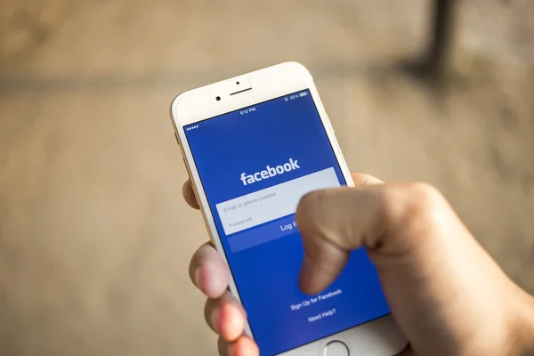 CHIANG MAI, THAILAND - JANUARY 04, 2015: A man trying to log in Facebook application using Apple iPhone 6. Facebook is largest and most popular social networking site in the world. — Stock fotografie