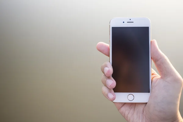 Mann hält Smartphone vor glatten Hintergrund. — Stockfoto