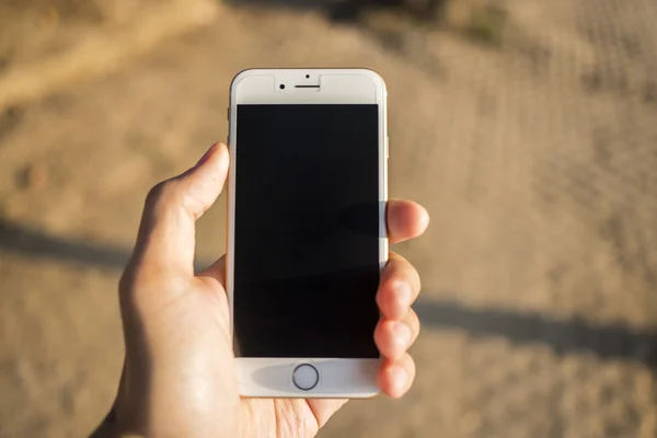 Uomo mano smartphone contro su sfondo sfocato . — Foto Stock