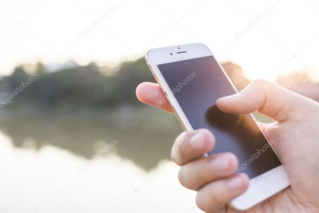 Man hand holding smartphone against on smooth background.