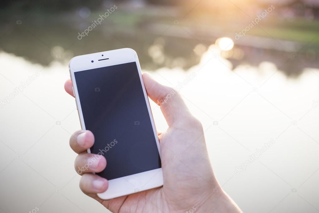 Man hand holding smartphone against on smooth background.